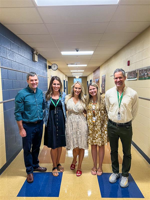group of five teachers smiling in the hallway